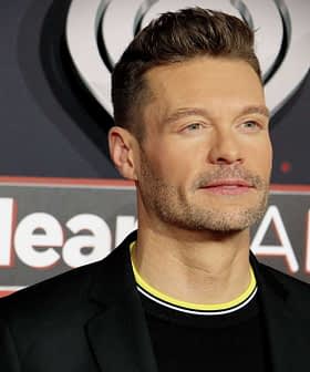 Man wearing a black suit with a yellow collar at an iHeartRadio event red carpet. - Olive Oil Times