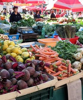 Display of fresh vegetables and fruits including beets, carrots, and lemons at a market stall. - Olive Oil Times