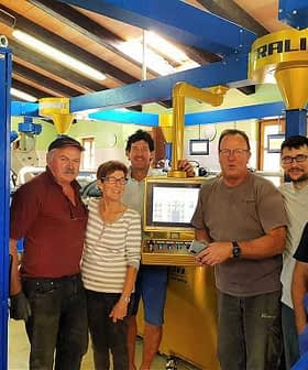 Six individuals standing in an olive oil production facility near machinery and equipment. - Olive Oil Times