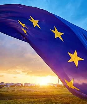 European Union flag with stars waving against a sunset sky with clouds. - Olive Oil Times