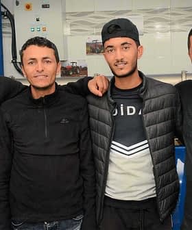 Four men wearing black clothing posing together in a casual setting. - Olive Oil Times