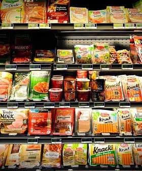 Various packaged food items displayed on a grocery store shelf, including meats and snacks. - Olive Oil Times