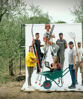 Group of six individuals posing with various gardening tools in an olive grove setting. - Olive Oil Times