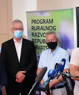 A group of four individuals standing together at a press conference, wearing masks and formal attire. - Olive Oil Times