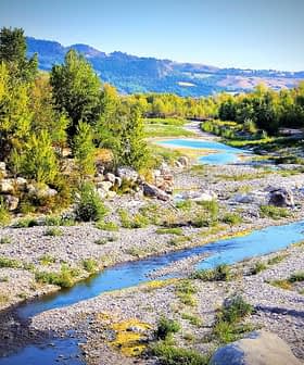 A river winding through a landscape with trees and rocky areas under a clear sky. - Olive Oil Times