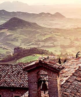 View of rooftops with a mountainous landscape in the background during sunset. - Olive Oil Times
