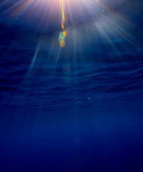 Sunlight filtering through water, creating rays and reflections in a deep blue ocean. - Olive Oil Times