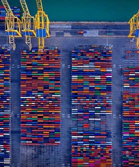 Aerial view of a shipping container yard filled with colorful containers arranged in rows. - Olive Oil Times
