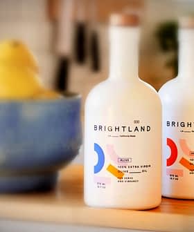 Two bottles of Brightland extra virgin olive oil with a blue bowl of lemons in the background. - Olive Oil Times
