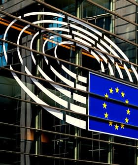 European Union flag displayed on the glass exterior of a building with circular design elements. - Olive Oil Times