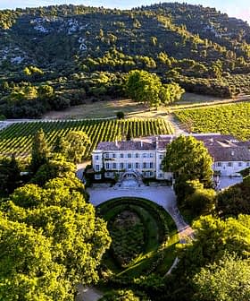 Aerial view of Chateau d'Estoublon surrounded by vineyards and trees. - Olive Oil Times