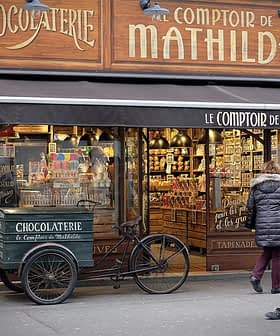 Shopfront of Le Comptoir de Mathilde featuring a chocolatier display and a bicycle cart. - Olive Oil Times