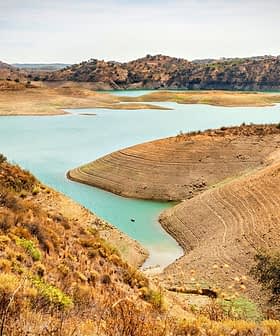 A view of a reservoir with a dry shoreline and surrounding hills in a natural landscape. - Olive Oil Times