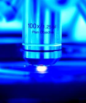 Close-up of a microscope objective lens labeled 100x with a blue background. - Olive Oil Times