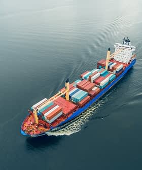 Aerial view of a container ship carrying colorful cargo containers on calm water. - Olive Oil Times