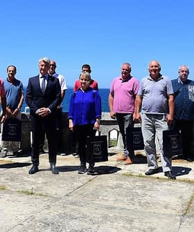 A group of individuals standing together outdoors with a clear blue sky in the background. - Olive Oil Times