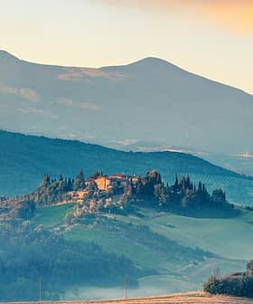 A scenic view of a Tuscan landscape featuring rolling hills and a farmhouse on a hilltop. - Olive Oil Times
