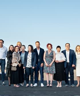 A group of individuals standing together outdoors for a photo against a clear sky. - Olive Oil Times