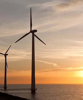 Row of wind turbines along the coastline during sunset with a colorful sky. - Olive Oil Times