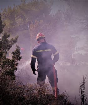 Firefighter wearing protective gear working in a smoky environment during a fire response operation. - Olive Oil Times