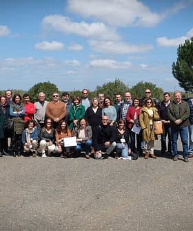 Group photo of a diverse gathering of people standing outdoors in a rural setting. - Olive Oil Times