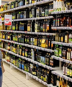 Individual looking at various bottles of olive oil on a supermarket shelf. - Olive Oil Times