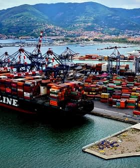 A large container ship named NYK LINE docked at a busy port surrounded by colorful shipping containers. - Olive Oil Times