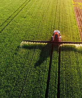Aerial view of an agricultural sprayer applying treatment to a green field. - Olive Oil Times