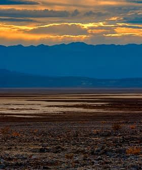 A desert landscape featuring mountains and a sunset with clouds in the sky. - Olive Oil Times