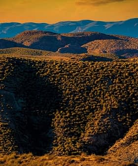 A view of a mountainous landscape featuring rolling hills and vegetation under a sunset sky. - Olive Oil Times