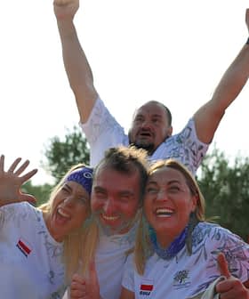 Four individuals celebrating outdoors with expressions of joy and excitement, two in the foreground and two in the background. - Olive Oil Times