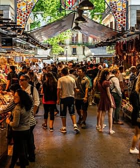 A busy market scene with numerous stalls selling a variety of goods and many people browsing. - Olive Oil Times