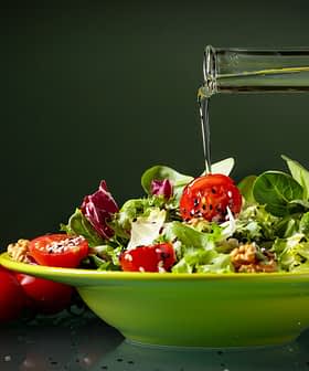 A bowl of mixed salad with cherry tomatoes and olive oil being poured over it. - Olive Oil Times