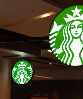 Illuminated Starbucks logo sign featuring a green background and white mermaid design. - Olive Oil Times
