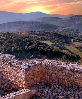Stone ruins overlooking a mountainous landscape during sunset with a colorful sky. - Olive Oil Times