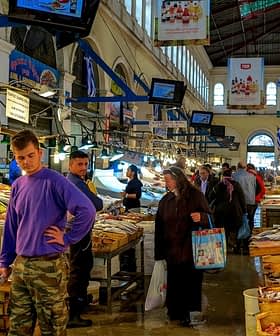 Interior view of a fish market with customers browsing and vendors displaying seafood. - Olive Oil Times