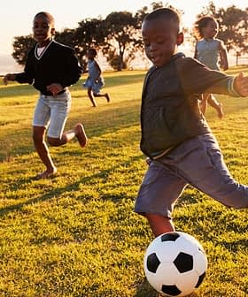 Group of children running and playing soccer on a grassy field during sunset. - Olive Oil Times