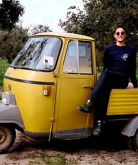 A person sitting on a yellow three-wheeled vehicle in an outdoor setting with trees. - Olive Oil Times