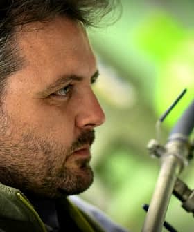 Profile view of a man with a beard, wearing a green jacket, observing equipment. - Olive Oil Times