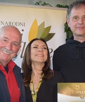 Three individuals posing together while holding a diploma at an event. - Olive Oil Times