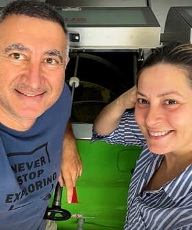 Two individuals smiling while standing next to machinery in a workshop environment. - Olive Oil Times