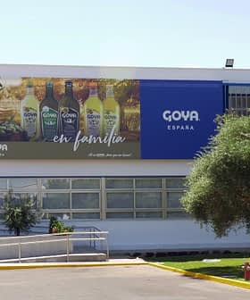 Exterior view of the Goya España building featuring a large advertisement and olive trees. - Olive Oil Times