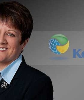 A business executive in a black suit with a light blue shirt, smiling against a dark background with the KeHE logo. - Olive Oil Times