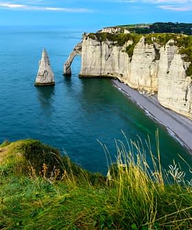 Cliffs and a prominent rock formation in the sea at Etretat, France, under a clear blue sky. - Olive Oil Times