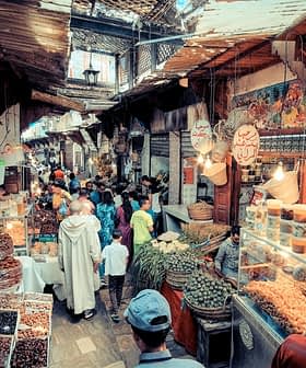 A bustling market scene in a traditional bazaar with various stalls and shoppers. - Olive Oil Times