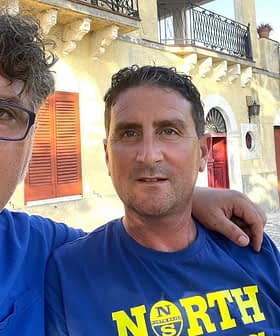 Two men posing for a selfie while holding a bottle of olive oil outdoors. - Olive Oil Times