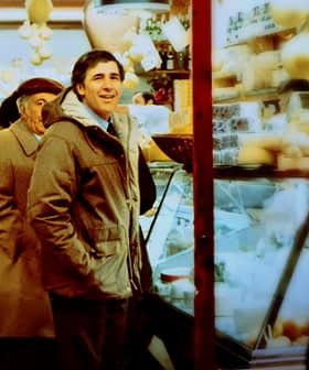 Two men standing in a market with shelves displaying various food items and products. - Olive Oil Times