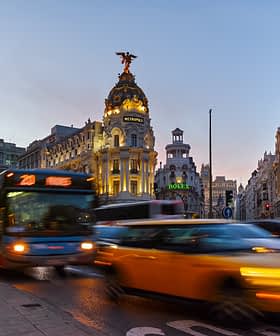 Buses and taxis moving through a busy street in Madrid during sunset. - Olive Oil Times