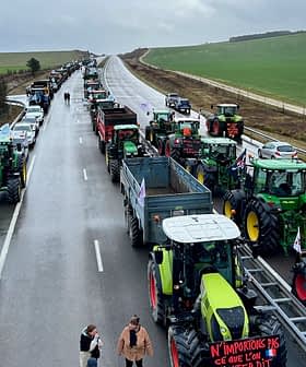 Line of tractors on a highway during a protest with people walking nearby. - Olive Oil Times