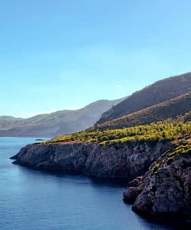 Coastal view featuring cliffs and calm water under a clear blue sky. - Olive Oil Times